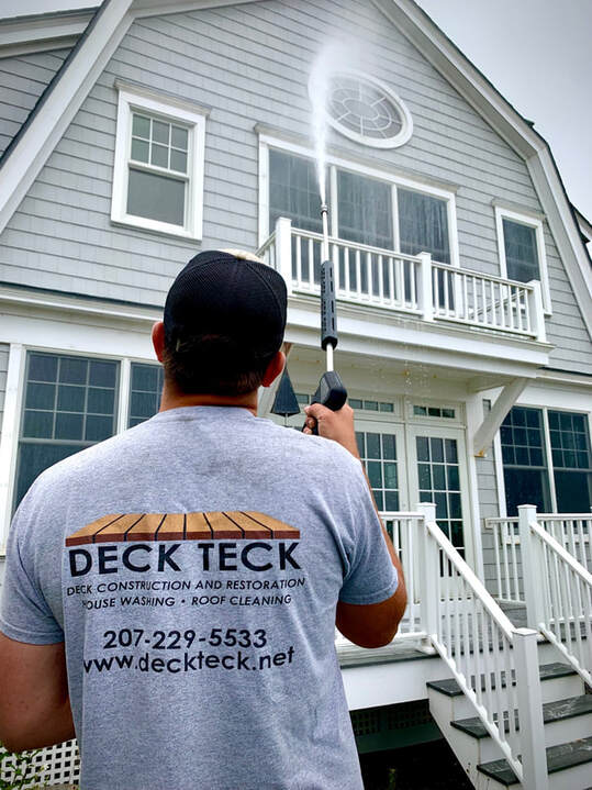 Deck Teck professional cleaning the front of a beachfront home with a spray wand